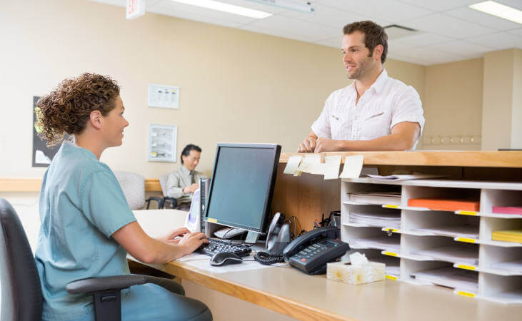 Nurse and patient conversing at reception desk in hospital