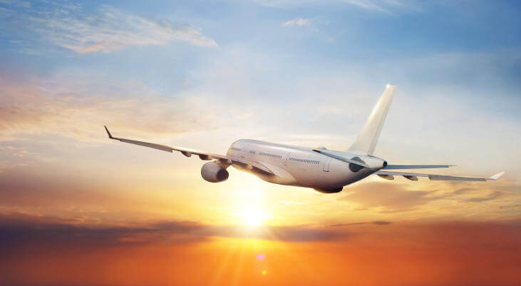 Big commercial airplane flying above clouds in sunset